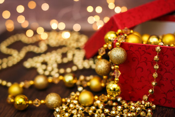 Close up golden christmas decoration balls from red gift box on dark wooden background and bokeh garland