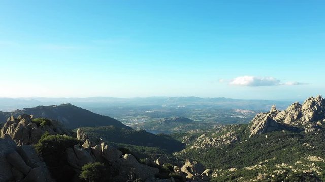 Video from above, aerial view of a beautiful valley surrounded by granite mountains and green vegetation, Monte Limbara, Sardinia, Italy.