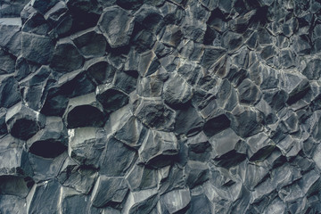 Fototapeta premium Basalt stone columns close-up on Reynisfjara black beach near Vik town, Iceland. Texture and background, vintage effect.
