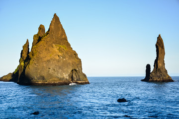 Reynisfjara black sand beach and rocks near  Vik town, Iceland at sunset on sunny summer day
