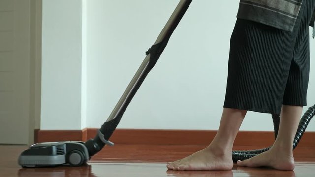 Woman cleaning house with vacuum cleaner. Beautiful Asian woman cleaning floor with vacuum cleaner. Low angle shot. House cleaning service concept.
