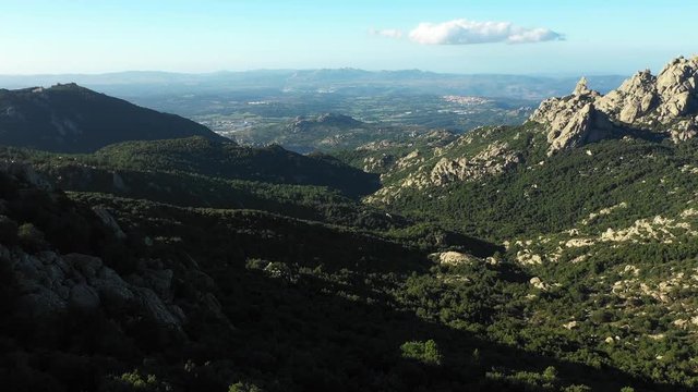 Video from above, aerial view of a beautiful valley surrounded by granite mountains and green vegetation, Monte Limbara, Sardinia, Italy.