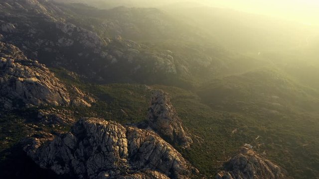 Video from above, aerial view oa a spectacular sunset behind some granite mountains in Sardinia, Italy.