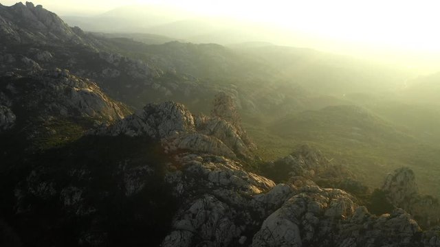 Video from above, aerial view oa a spectacular sunset behind some granite mountains in Sardinia, Italy.