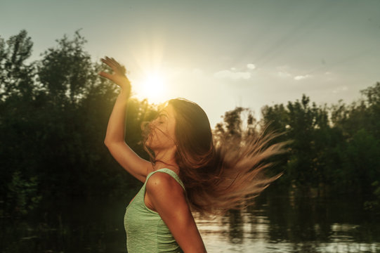 Beautiful young woman running on a riverside at sunset