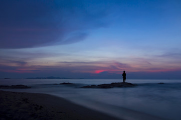 Obraz premium Colorful sky over sea and beach with man silhouette.