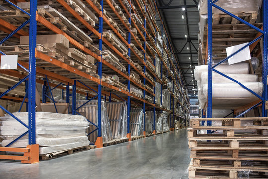 Large hall of logistic warehouse, many shelves with pallets and goods