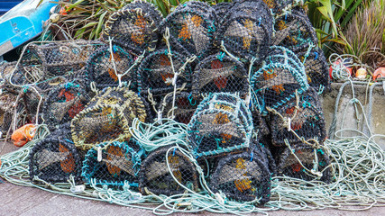 lobster traps piled up with ropes, buoys along Irish coast 