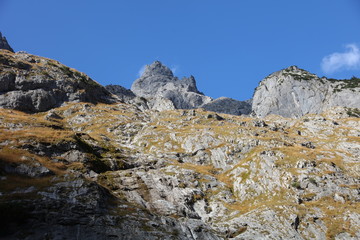 Fototapeta premium Sun and cloud shadows on mountain with autumn colors in German Alps