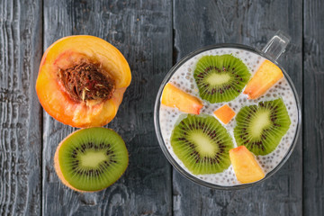 Half peach, half kiwi and Chia seed pudding on a dark wooden table. The view from the top. Flat lay.