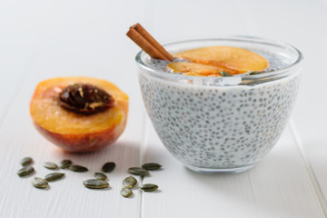 Half peach, cinnamon stick, pumpkin seeds and Chia seed pudding on wooden table.
