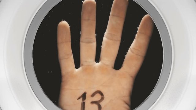 hand with the inscription on the palm: 13, appears in the illuminator from the dark depths, close-up