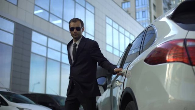 Responsible driver helping boss get out of car, lady walking to office meeting