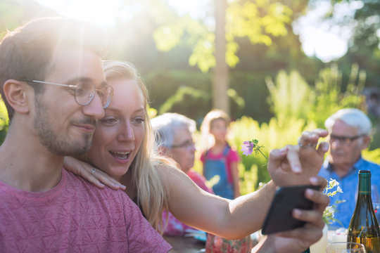 During a family bbq a young couple does a selfie on their phone
