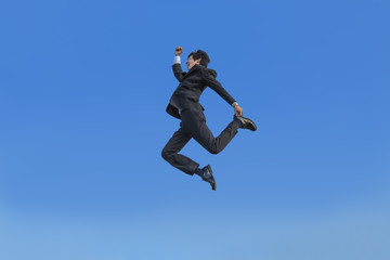 Fototapeta na wymiar 青空をバックに空中を走るスーツ姿の若いビジネスマン1人。元気・健康・発展・挑戦イメージ