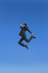 Fototapeta na wymiar 青空をバックに空中を走るスーツ姿の若いビジネスマン1人。元気・健康・発展・挑戦イメージ