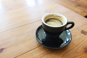 Coffee cup of Espresso Americano in black mug ceramic on the soft brown wood table background