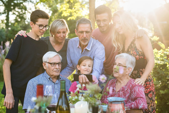 During a bbq, the family have fun sharing a video on a phone