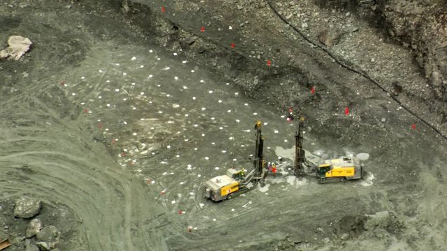 Drilling machines drilling holes in mine quarry for explosives.