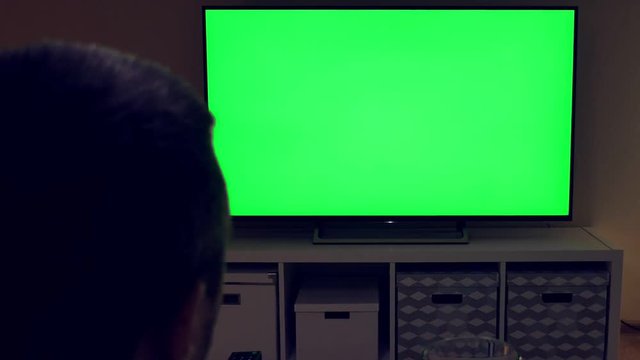 Watching tv with green screen at home interior. Evening