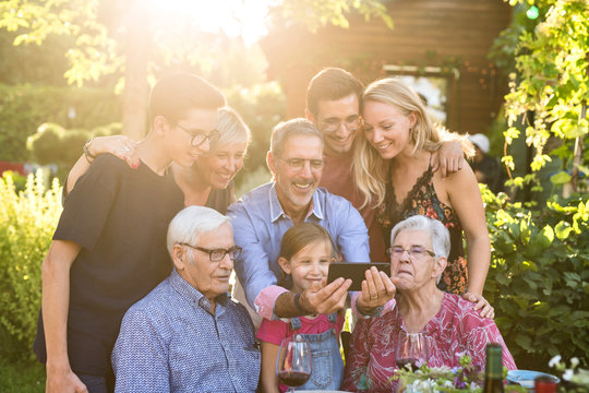 During a bbq, the family have fun sharing a video on a phone