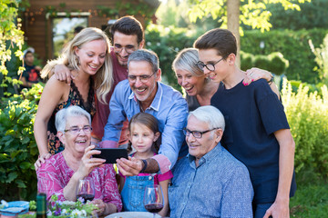  During a bbq, the family have fun sharing a video on a phone