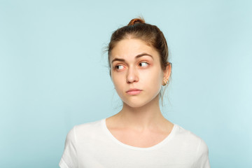 emotion face. doubtful dubious uncertain insecure thoughtful woman looking sideways. young beautiful brown haired girl portrait on blue background.