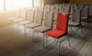 One red chair different from others in empty conference room