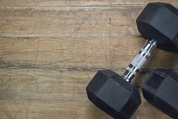 Two black dumbbells on a wooden background in the gym