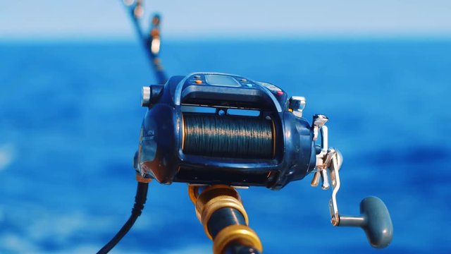 Rack focus close up from fishing rod to big game reel trolling in Caribbean Sea