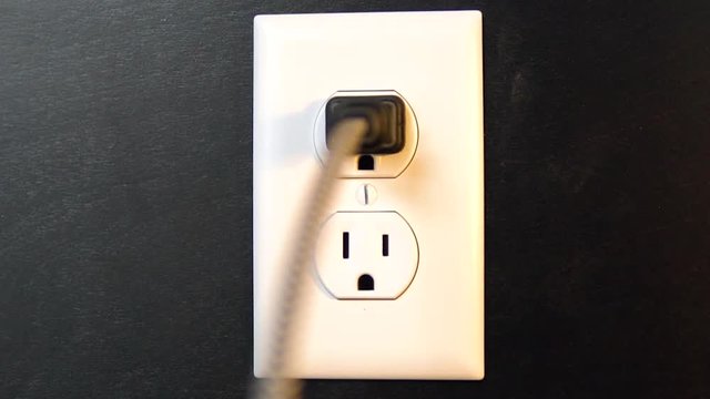 Light turns on and off as a cord is plugged into the top outlet and removed from an American electrical socket