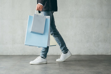 shopping for clothing. male fashion and style. casual guy walking holding lots of bags with goods.