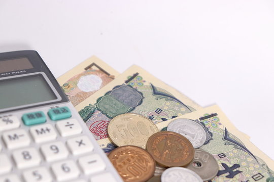 白背景に日本のお金(お札と小銭)と計算機