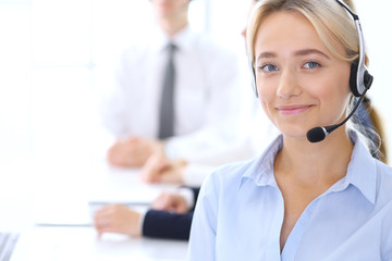 Group of call center operators at work. Focus at blonde beautiful business woman in headset