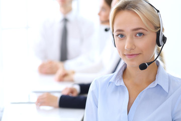 Group of call center operators at work. Focus at blonde beautiful business woman in headset