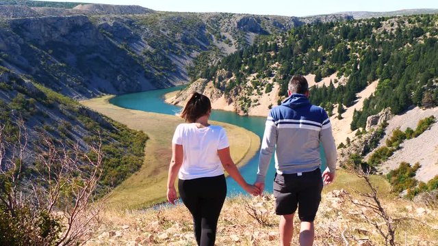 Young couple holding hands and walking together at Zrmanja canyon and watching river.