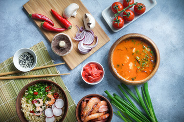 Asian food, Tom Yam and Ramen with shrimps, Thai food in wooden bowl, Egg noodles, Preparation, Chilli peppers, onion and mushrooms, Spicy, Top view on light gray background, Selective focus