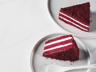 Piece of red velvet cake with perfect texture in matte plate on white marble tabletop. Slice of...