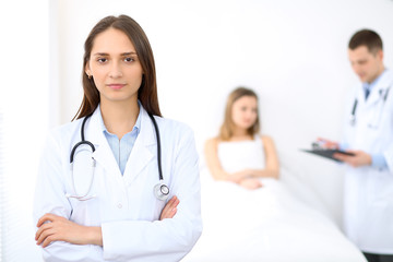 Fototapeta premium Medicine doctor standing and smiling on the background with patient in the bed