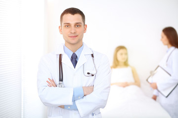 Fototapeta premium Medicine doctor standing and smiling on the background with patient in the bed