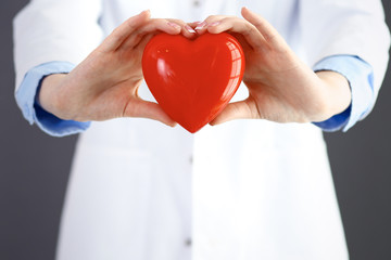 Female doctor with stethoscope holding heart in her arms. Healthcare and cardiology concept  in...