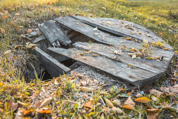Old abandoned well with a broken wooden lid. - 228245075