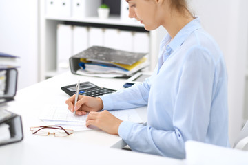 Unknown female bookkeeper or financial inspector calculating or checking balance, making report, close-up. Internal Revenue Service at work with financial document. Tax and audit concept