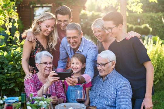 During a bbq, the family have fun sharing a video on a phone