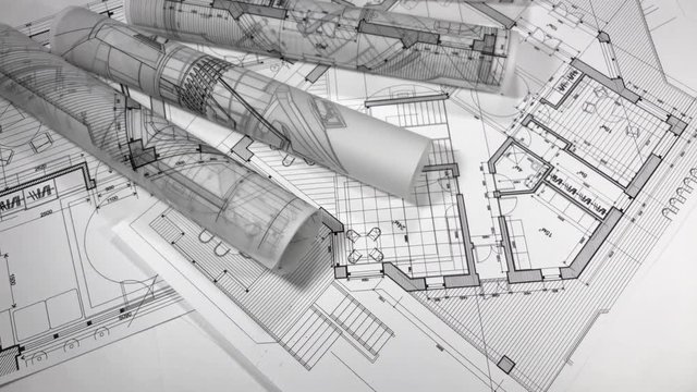 Blueprints - rolls of architectural drawings smoothly rotate on the surface of the architectural plan of a modern house / seamless looping