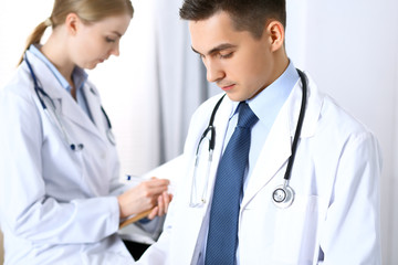 Fototapeta premium Doctors discussing medication records form or studying at medical conference. Healthcare, insurance and medicine concept