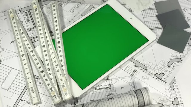 workplace of the architect: architectural plans of the modern house - blueprints, an electronic tablet with a green screen, a notebook and colored samples of materials - plastics