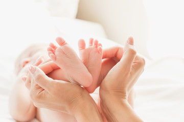 Fototapeta na wymiar Hands of woman and baby feet, soft focus background