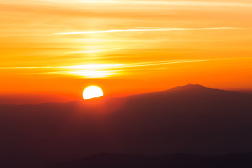 Beautiful sunset with sun coming down behind various layers of mountains