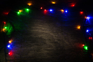 multicolored Christmas lights on a wooden background